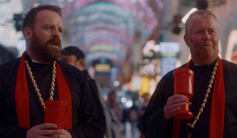 two men dressed as priests holding charity collection buckets