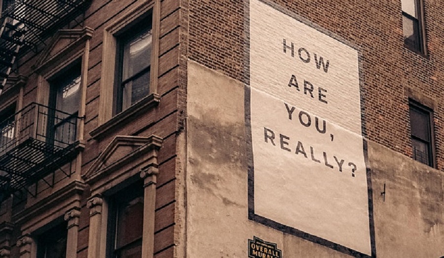 poster on a brick wall reading 'how are you really?'