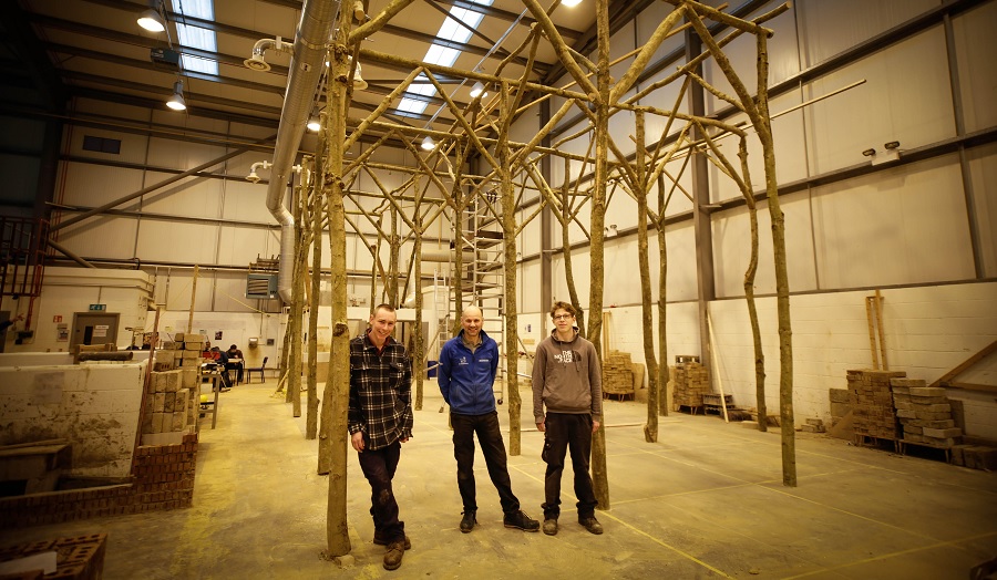 three men standing with wooden structure