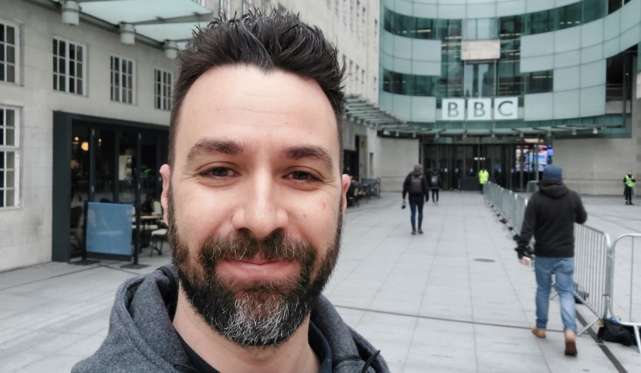 man with a beard, smiling, standing outside the BBC building