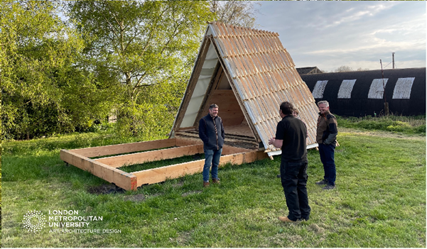 Three people standing in front of wooden modular cabin 