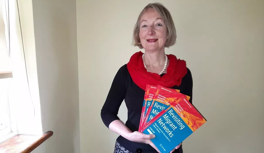 Professor Louise Ryan holding copies of books called Revisiting Migrant Networks