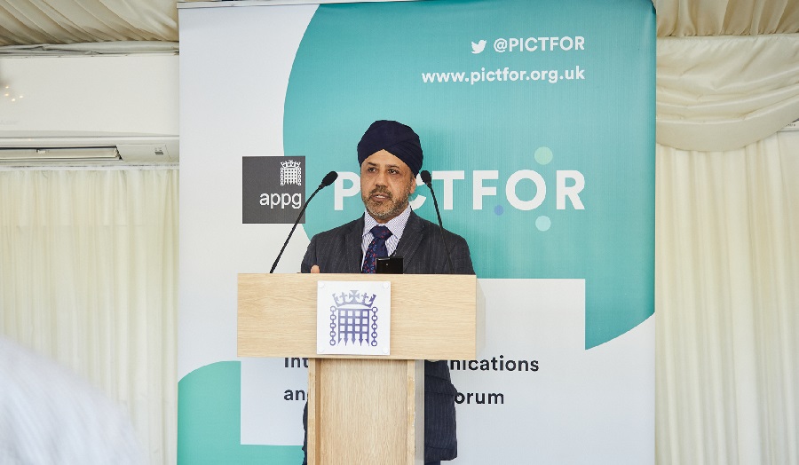 Bal Virdee speaking at a podium, in front of a banner reading 'PICTFOR'