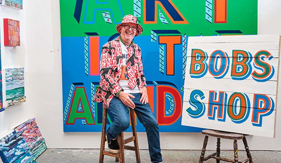 Bob and Roberta Smith/Patrick Brill sat on a stool in front of the Tate shop