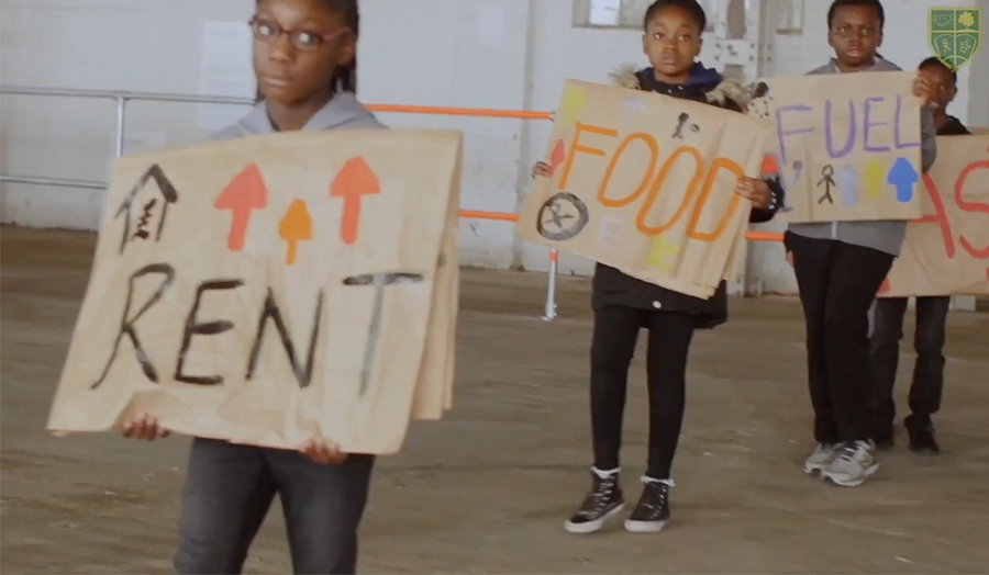 Students from St Antony's Catholic Primary school holding signs with 'rent' 'food' and 'fuel'