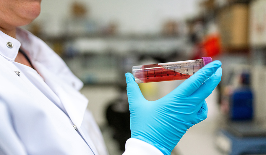 Scientist holding up a vial in a laboratory setting