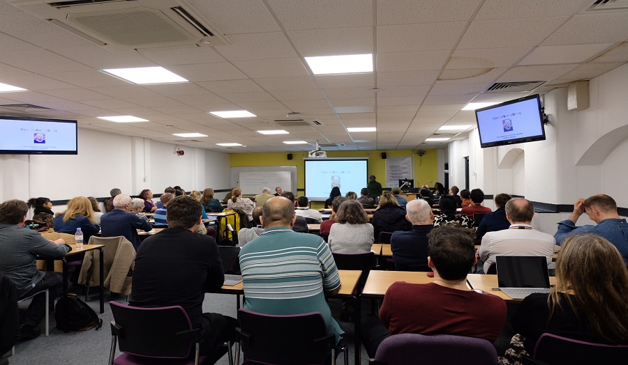 Staff members in a classroom sat in a row facing a lecturer during the Teaching and Learning Forum