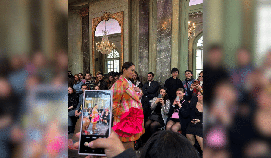 A picture of someone taking a picture of a model on the catwalk at Paris Fashion Week