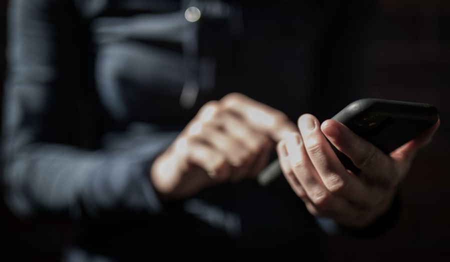 Hands holding a phone in a dark room