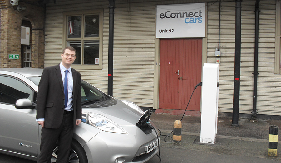 Man stands with electric vehicle on charge