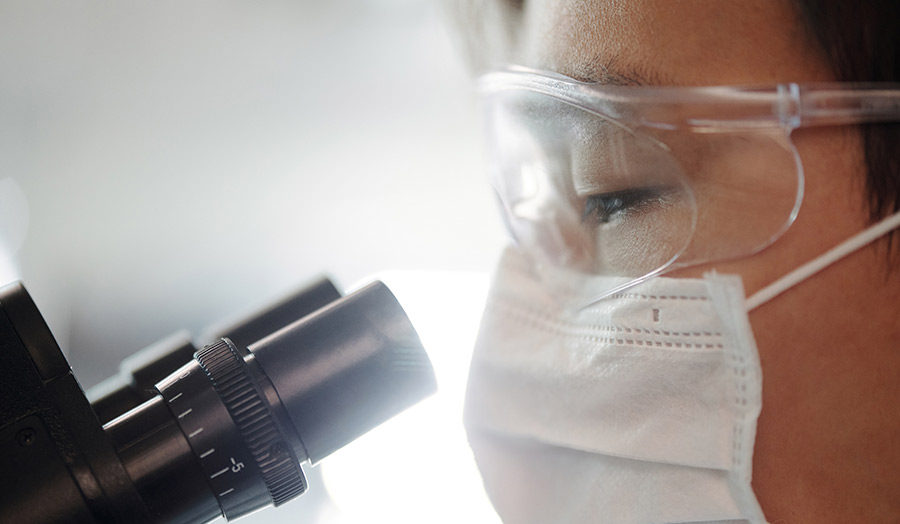 A close up of a research nurse looking through a microscope