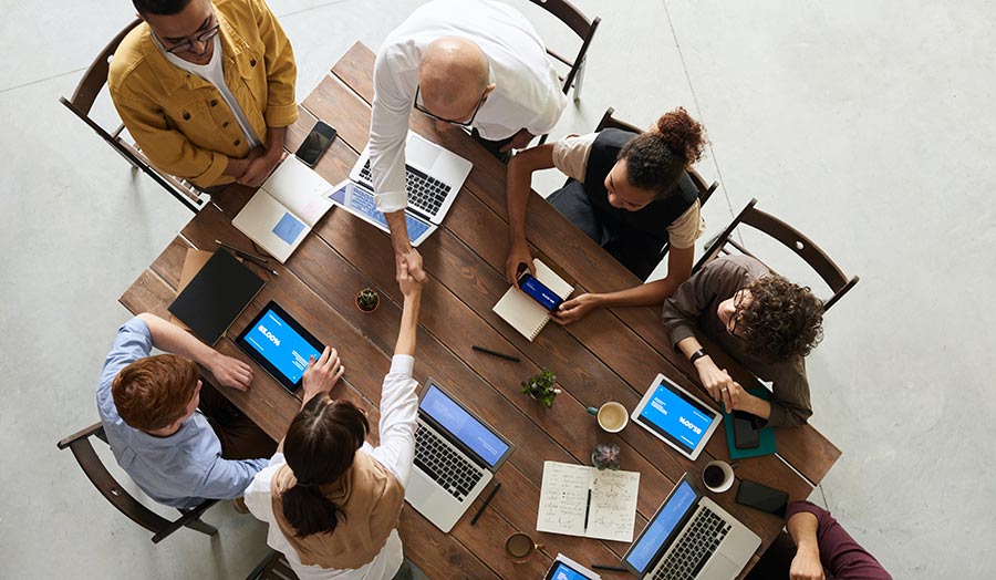 People sitting around a table and two shake hands as when a deal is agreed