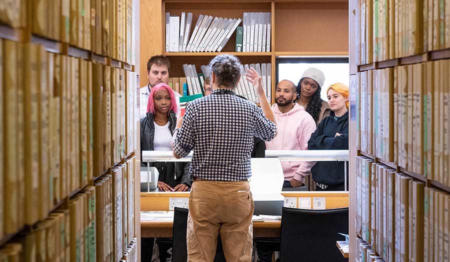 A group of students circled around lecturer in a library