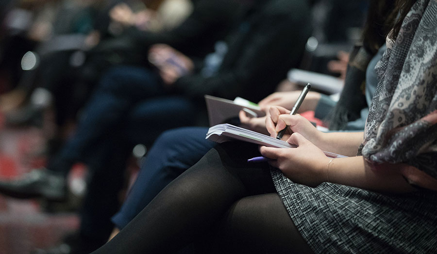 People sitting at conference taking notes