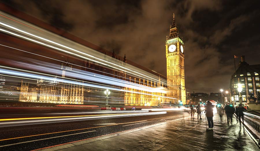 Houses of Parliament from Westminster Bridge at night with rays of lights from passing cars