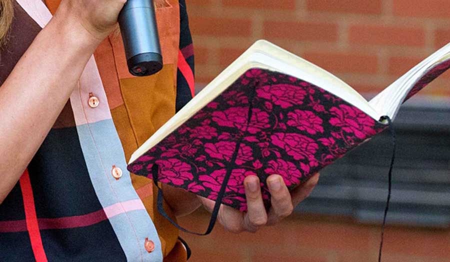 woman holding a microphone and reading from a book