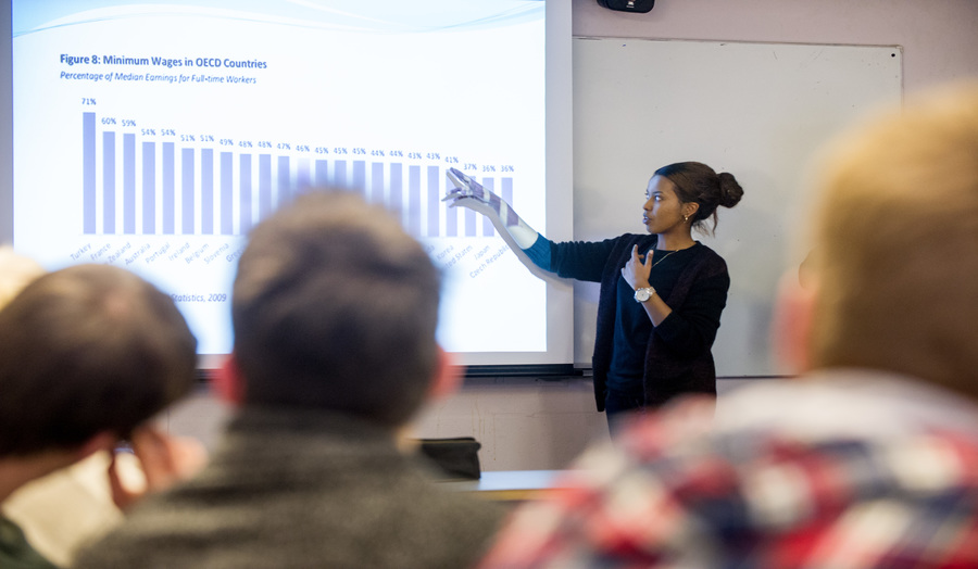 female academic presenting in front of the group, pointing at the chart