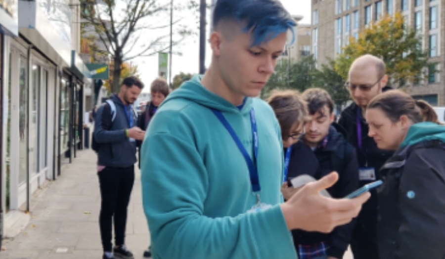 Games students on Holloway Road, checking their mobile phones for monster clues