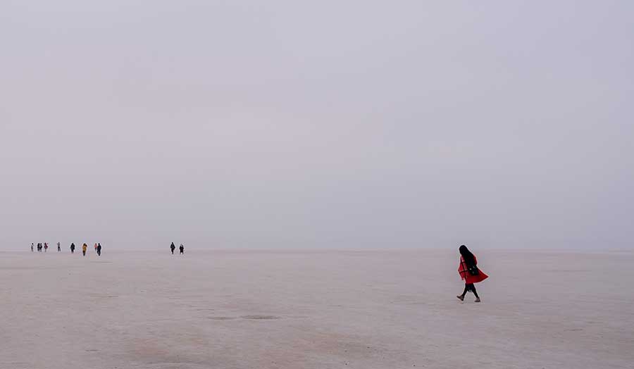 a women in a headscarf walking through the desert 