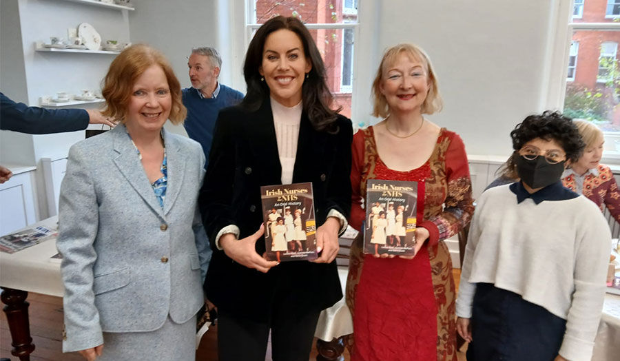 Four people smiling and holding copies of the book Irish Nurses in the NHS