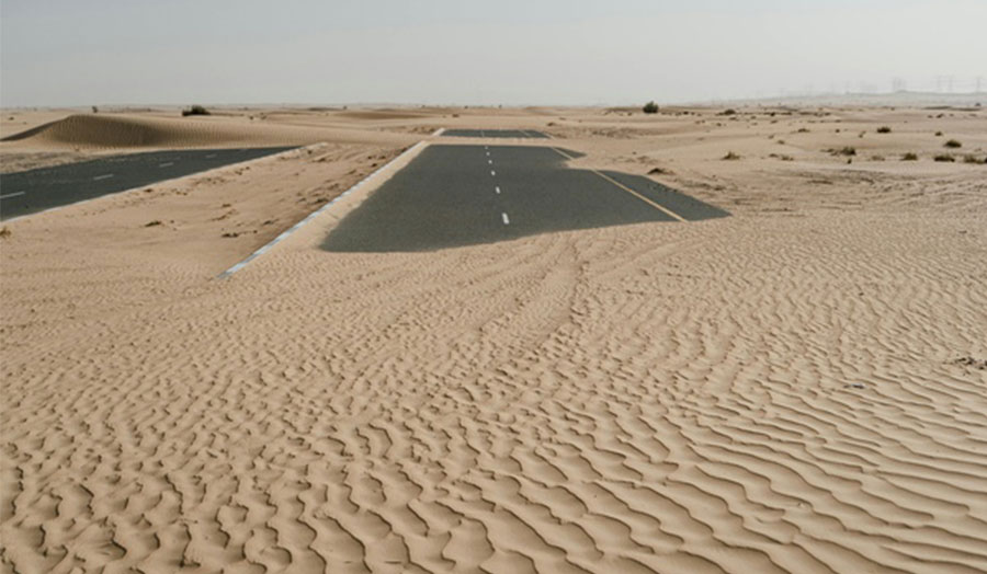 Sand dunes partially covering an abandoned road