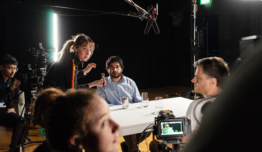 A group of people in a dark studio prepare to start filming