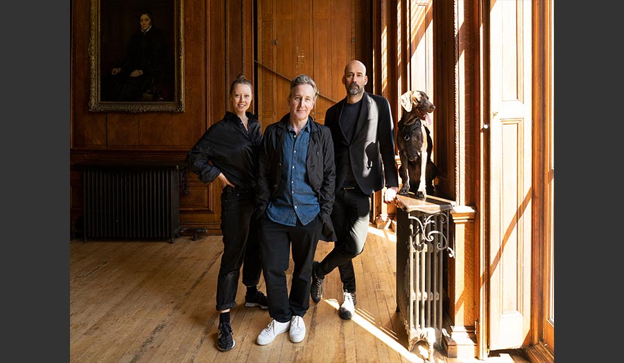 Three people and a dog in a wood-panelled room