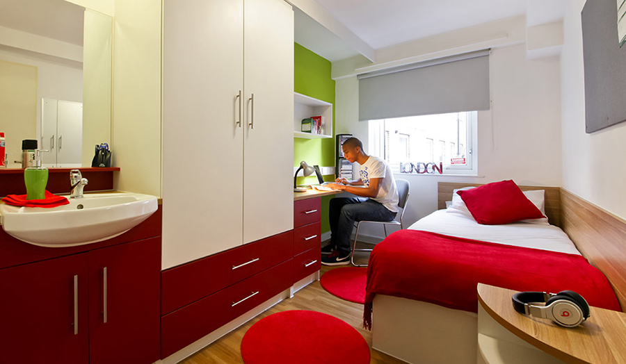 Student sitting at desk on laptop in room at The Arcade Hall of residence.