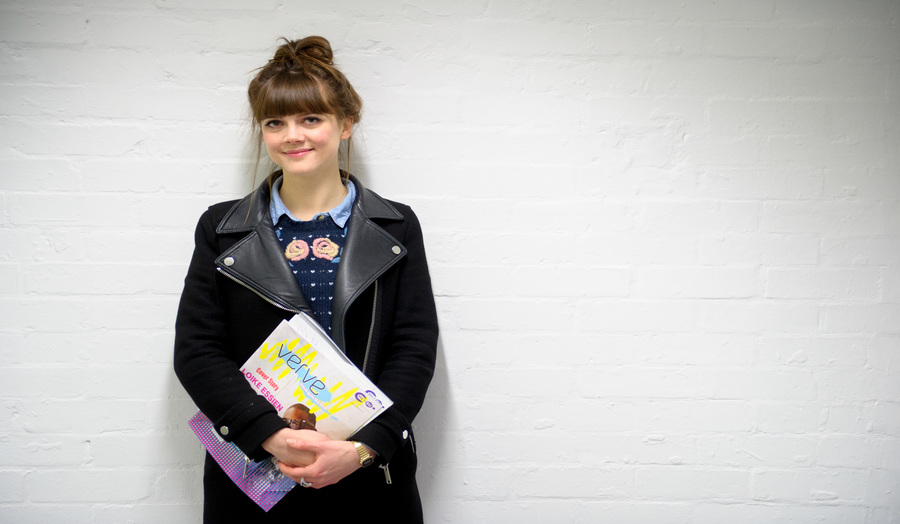 A female London Met student standing against a wall