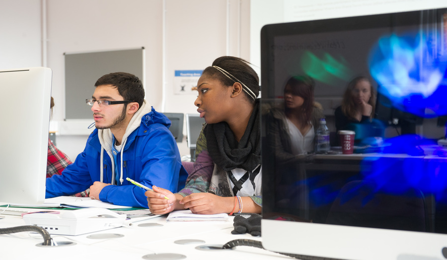 Two students working on a computer in the library