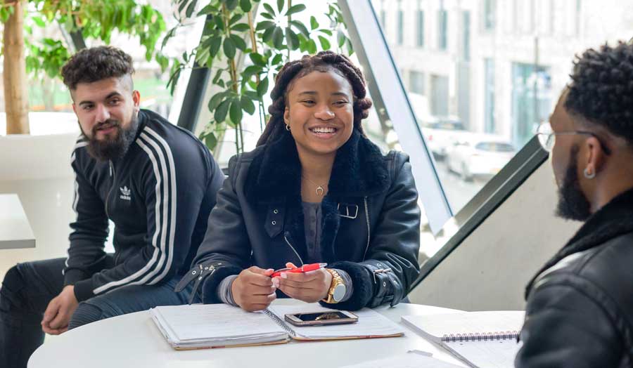 Three students sat together in conversation 