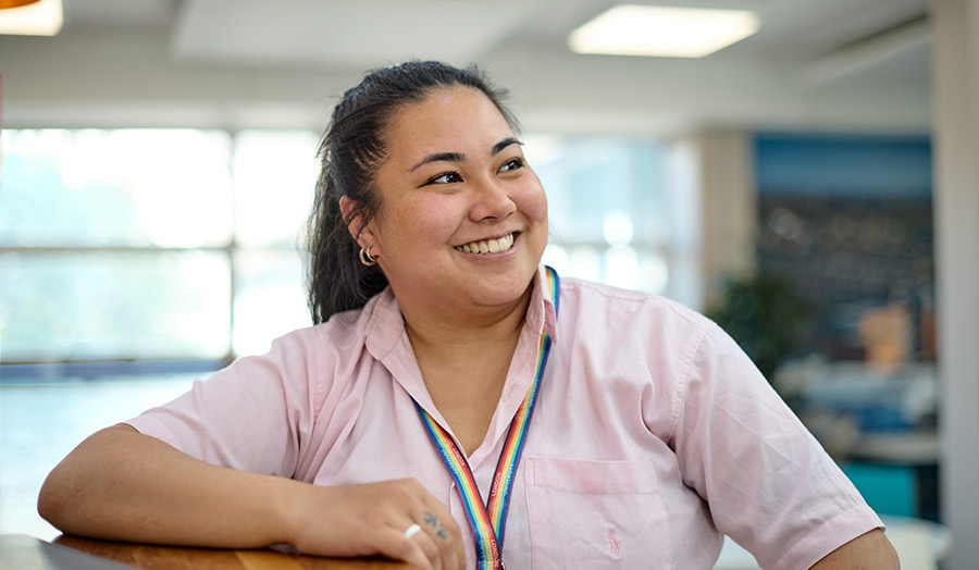 Chrystalle pictured smiling and wearing a rainbow lanyard
