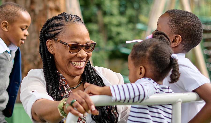 Denise smiling, playing with several of her children