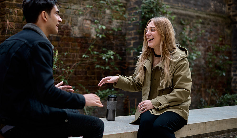 London Met Student Hailey laughing with a friend in a courtyard