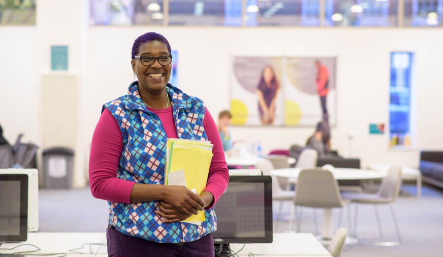 Janet Barnett standing in the library smiling