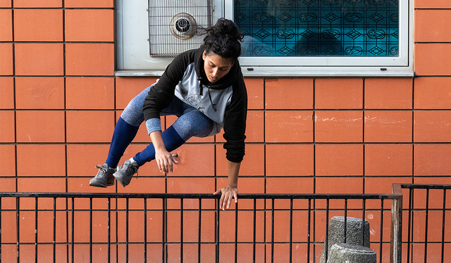 Kasturi Torchia jumping over a fence demonstrating Parkour