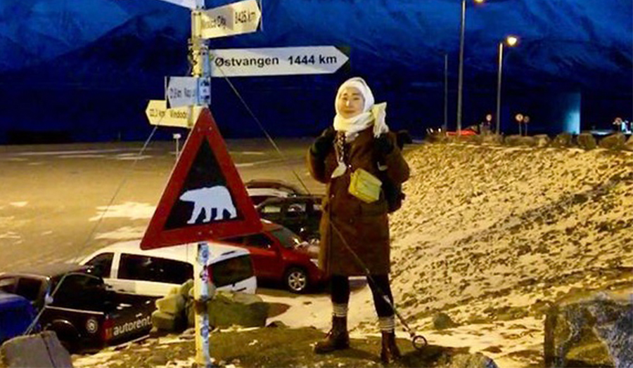Maiia Sivtseva in full winter clothing standing by various signposts in snow in Siberia