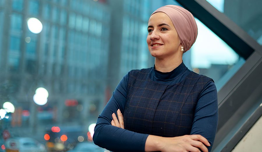 Photo of Nudzejma in London Met's graduate centre with blurred evening sky behind her