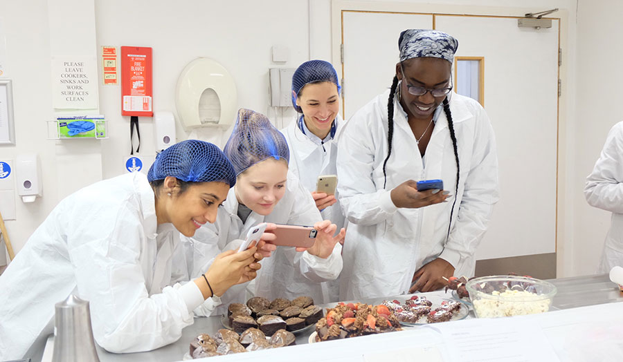 Students take photos of their completed food projects 