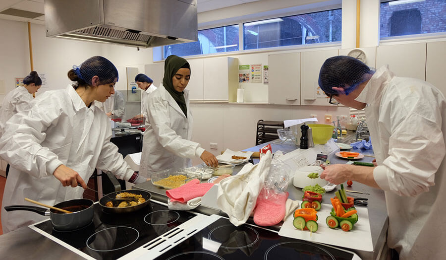 Students working at counters and hobs for their food projects